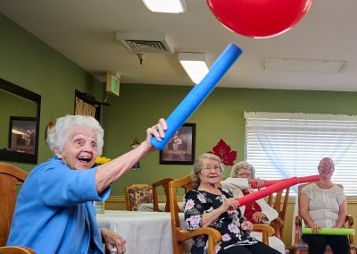 Elderly ladies playing a game with balloons and pool noodles at Vintage Faire